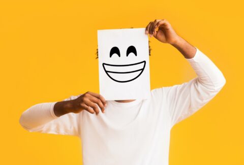 African american man holding paper with smiley face